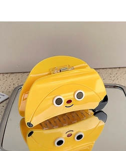 Close-up of a yellow cartoon hair claw clip on a mirror tray showing glossy texture