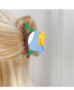 Detalle de una pinza para el pelo con forma de pájaro azul sobre cabello rubio