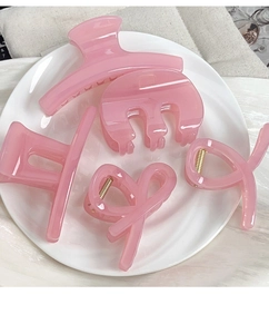 Detail of five pink resin hair claw clips with translucent texture on a white plate