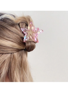 Detailed view of a pink iridescent star hair claw clip on light brown hair