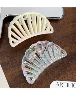 Detailed view of two iridescent semicircular hair claws on dark wood surface