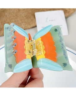 Detalle de una pinza para el pelo de mariposa colorida en acetato con muelle dorado