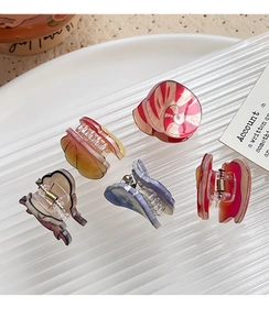 Set of five cute colorful acrylic shark hair clips on a white textured tray
