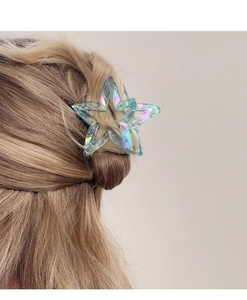 Close-up of holographic blue star-shaped hair claw clip on a braided hairstyle