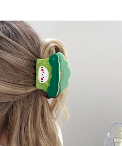 Detail of green acetate vegetable-shaped hair claw clip on long wavy brown hair