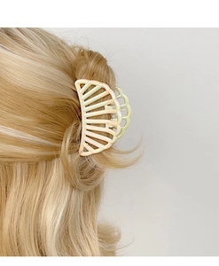 Detail of shell-shaped gradient claw clip holding a half-up hairstyle on blonde hair