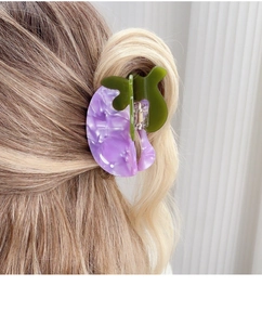 Detail of a large purple marble and olive green acetate hair claw clip on model hair