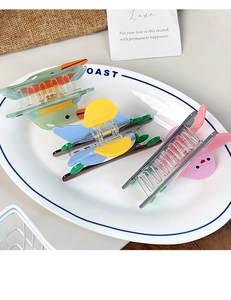 Primer plano de pinzas para el cabello con forma de pájaro y pato en un plato de cerámica blanca