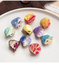 Close-up of colorful shell-shaped acrylic hair claws with a cute cartoon character design