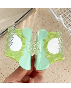 Close-up of a mint green wavy hair claw clip with acetate finish and metal spring mechanism