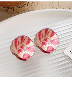 Detail of red and white acrylic spiral earrings on a white ceramic plate