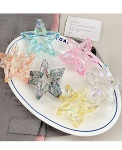 Collection of star-shaped iridescent hair clips in various colors on a white tray
