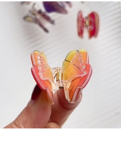 Detail view of a butterfly hair claw clip in orange gradient acrylic with metal spring