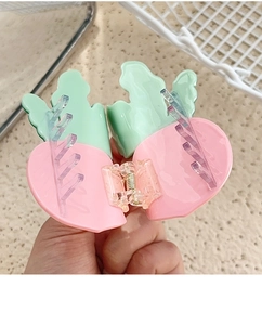 Close-up of pink vegetable-shaped acetate hair claw with green leaf detail and purple teeth
