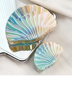 Close-up of iridescent shell-shaped hair claws with shiny pearl texture and ribbed details