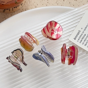 Set of 5 colorful acrylic claw clips with cute patterns on a white tray