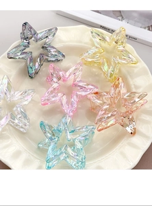 Group of star-shaped holographic hair claws in various crystal colors on ceramic plate