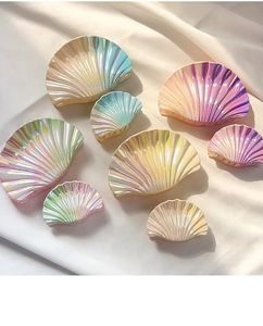 Detail of seashell hair claws in gradient pearlescent colors on white fabric