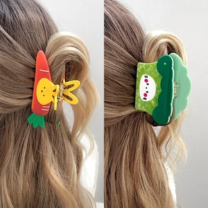 Cute cartoon vegetable hair claws featuring carrot and broccoli designs on wavy brown hair