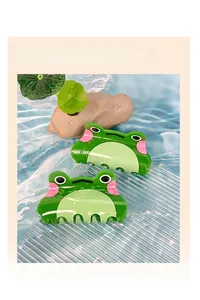 Détail de pinces à cheveux en forme de grenouille en acrylique vert dans un décor naturel