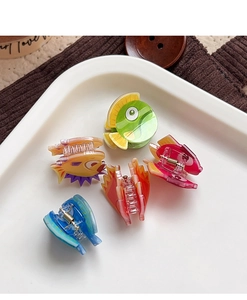 Détail de pinces à cheveux en forme de poisson coloré sur un plateau en céramique