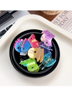 Colorful mini acrylic dinosaur hair clips in a black bowl on a desk setting