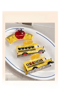 Close-up of school bus and ruler hair clips with crystals on a white ceramic plate