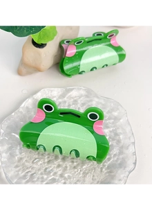 Détail de deux pinces à cheveux grenouille verte sur plateau en verre avec décor naturel