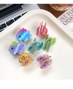 Close-up of seven colorful mini acrylic dinosaur hair clips in a white ceramic tray