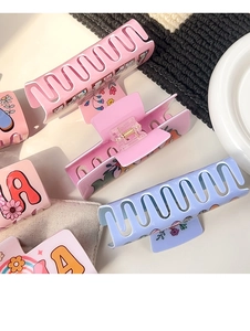 Detailed macro view of matte flower claw clips with vintage letters and floral patterns