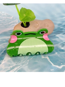 Détail d'une adorable pince à cheveux grenouille en acrylique vert avec gouttes d'eau réalistes
