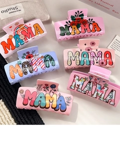 Detail of six colorful MAMA letter hair claws with floral and rainbow patterns on resin