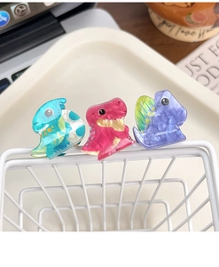 Close-up of cute acrylic dinosaur hair clips in cyan, pink, and lilac with marble texture