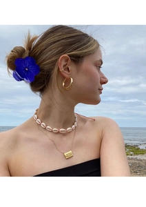 Detail view of sunflower hair claw and bohemian jewelry set against a beach background