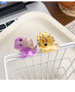 Detail of cute acrylic dinosaur hair clips in purple and yellow colors for girls