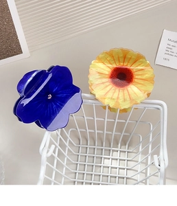 Detail view of blue and orange flower hair claws clipped on a white wire basket