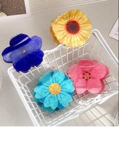 Detailed view of floral acrylic hair claws in assorted colors inside a white basket