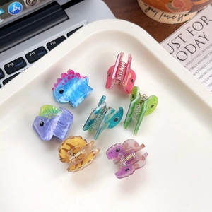 Set of six colorful acrylic dinosaur mini hair claws with glitter finish in a tray