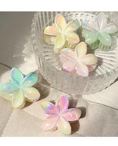 Detailed macro of five colorful gradient plumeria flower hair claws in a glass bowl