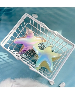 Macro detail of two gradient starfish hair clips in a beach-themed coastal display