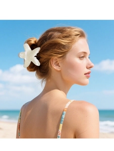 Close-up of a pearlescent starfish hair claw clip worn by a model at the beach