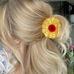 Floral sunflower hair claw clip with orange acetate petals shown on blonde curly hair