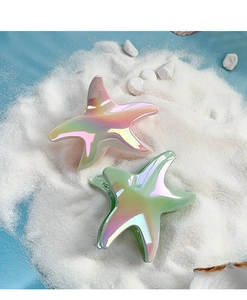 Detail of gradient starfish hair clips with iridescent finish on a beach sand background