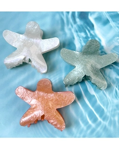 Detail of colorful starfish hair claws with pearlescent finish on blue water background