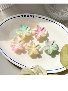 Set of five pearlescent frangipani flower hair claws in gradient macaron colors on a tray
