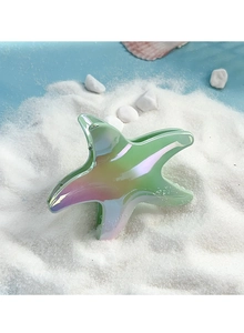 Detailed view of starfish claw clip with gradient laser finish on white beach sand