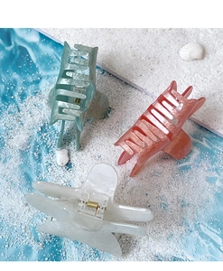 Close-up of star-shaped hair claws in mint green, coral pink, and pearl white marble textures
