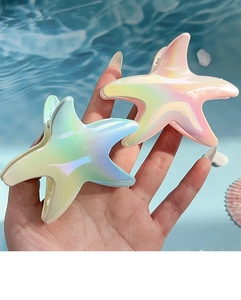 Close-up of holographic starfish hair claws in gradient blue and pink ocean style