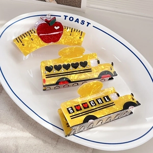 School style yellow hair claws with apple ruler and bus designs in a ceramic plate