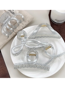 Detailed view of silver glitter resin hair claws in butterfly and geometric shapes